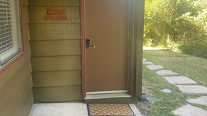 A brown door with a doormat and a welcome sign on the wall.