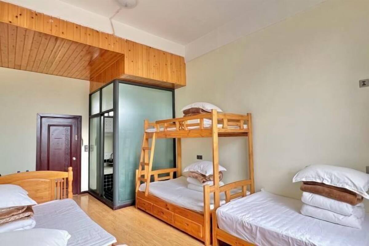 Une pièce avec des lits superposés, un plafond en bois, une porte et une petite table.