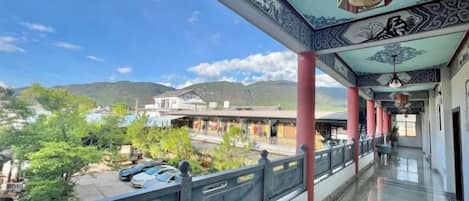 Un balcón techado con vista a un pueblo y montañas.