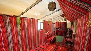 Ein Zimmer mit rot-schwarz gestreifter Wand, einem grünen Teppich und einer hölzernen Bank.