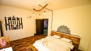Ein Schlafzimmer mit einem hölzernen Bett, einem Sessel, einer Wand mit Wandgemälde und einer Tür zu einem anderen Raum.