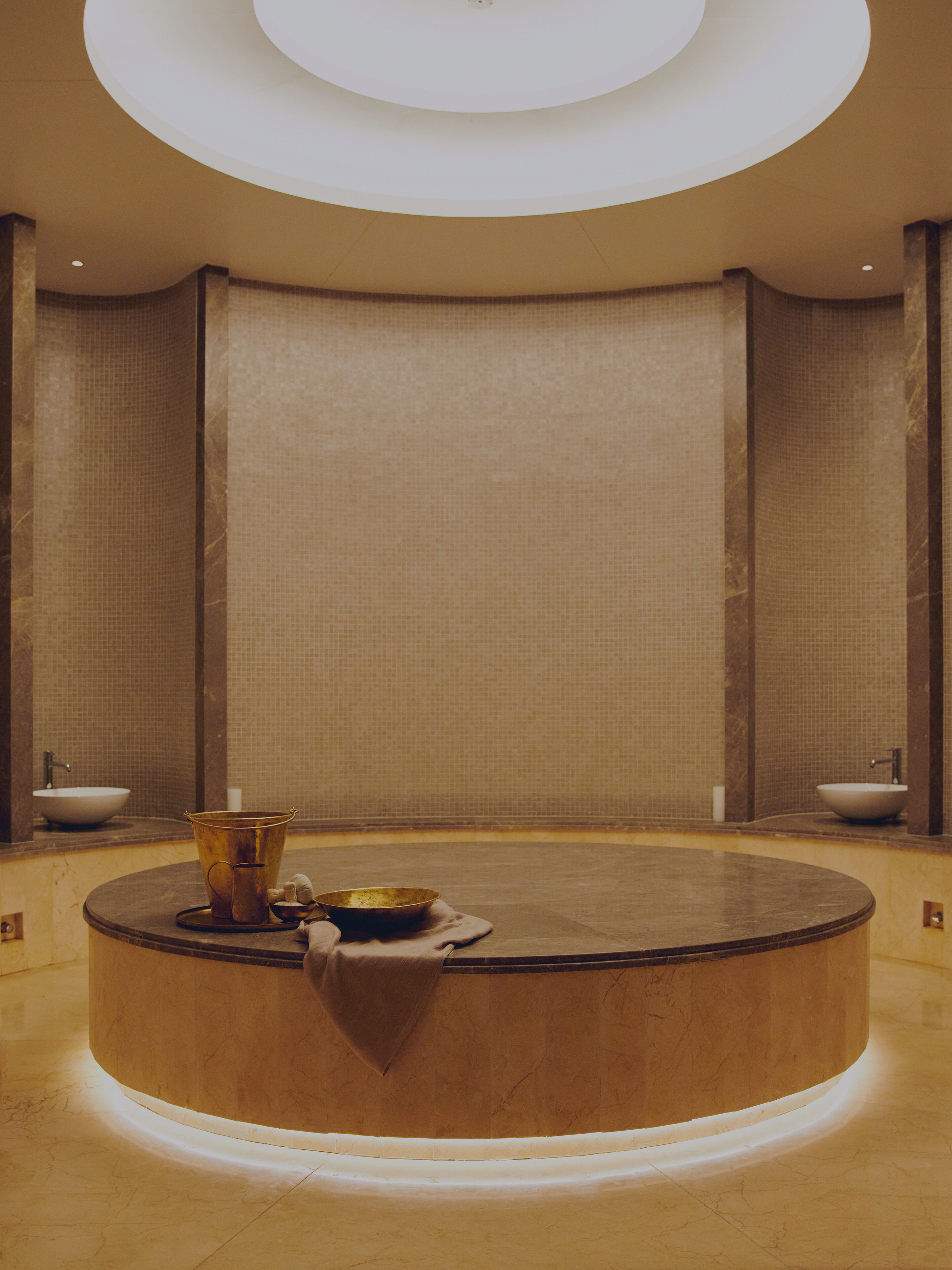 A circular spa area with a central hot tub, two sinks, and a bucket.