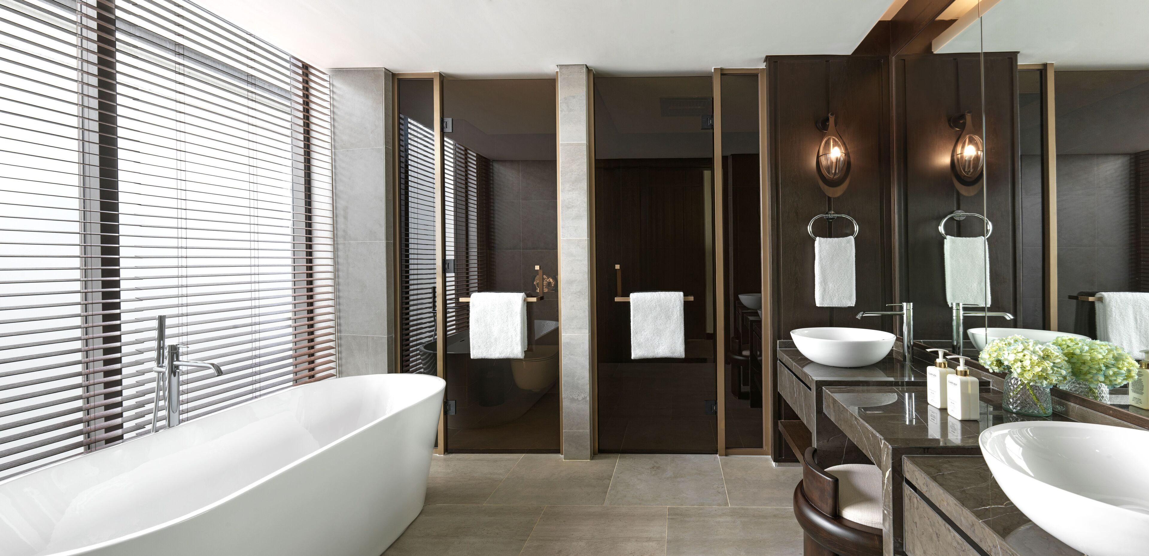 A modern bathroom with a freestanding bathtub, a large mirror, and a vanity with a sink and countertop.