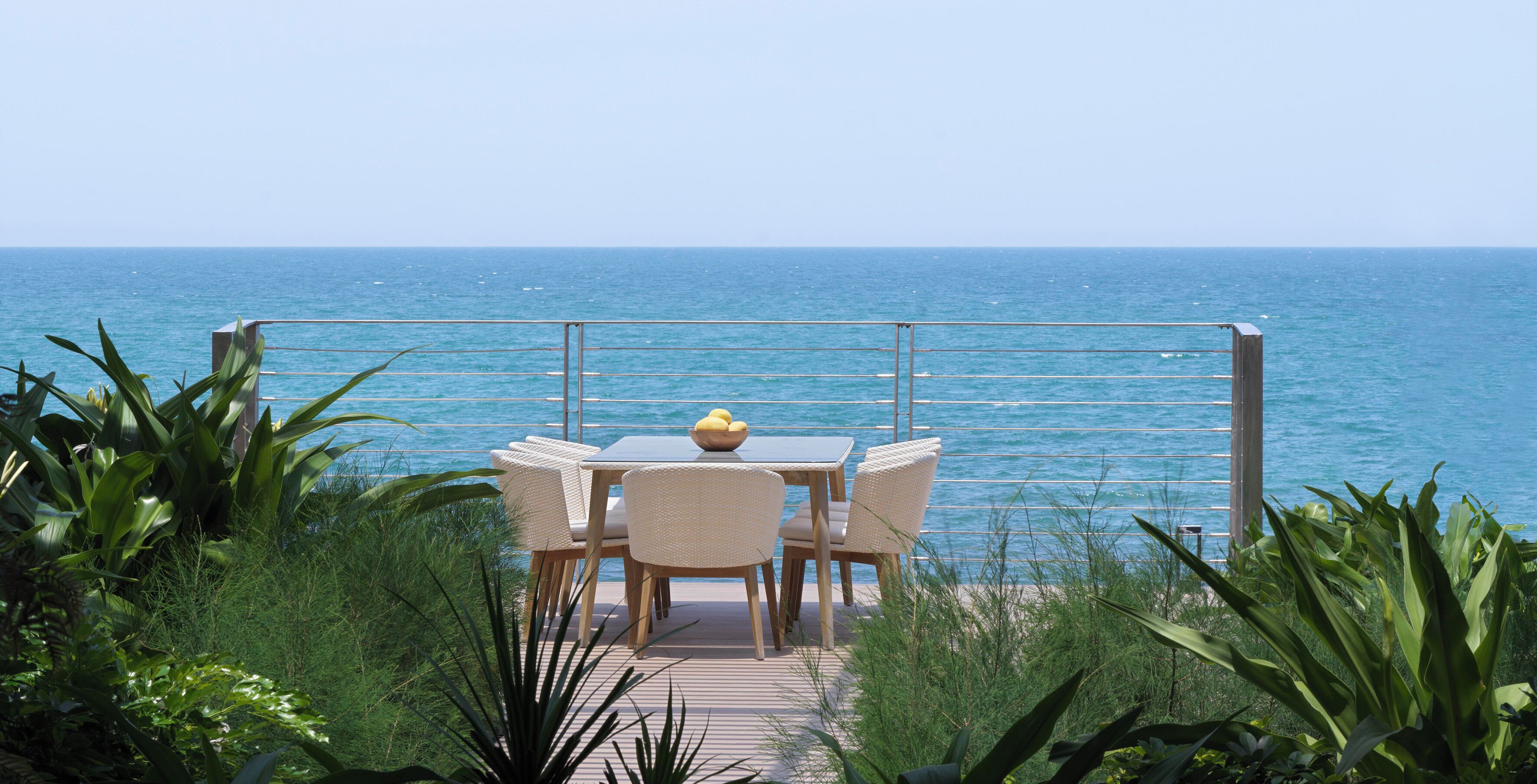 Una terraza con mesa y sillas que da al mar.
