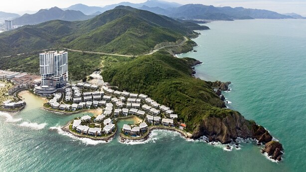 An aerial view of a coastal resort with a central high-rise hotel, connected resort buildings, and a surrounding natural landscape. - Villa Le Corail, A Gran Melia Hotel (Bac Nha Trang)