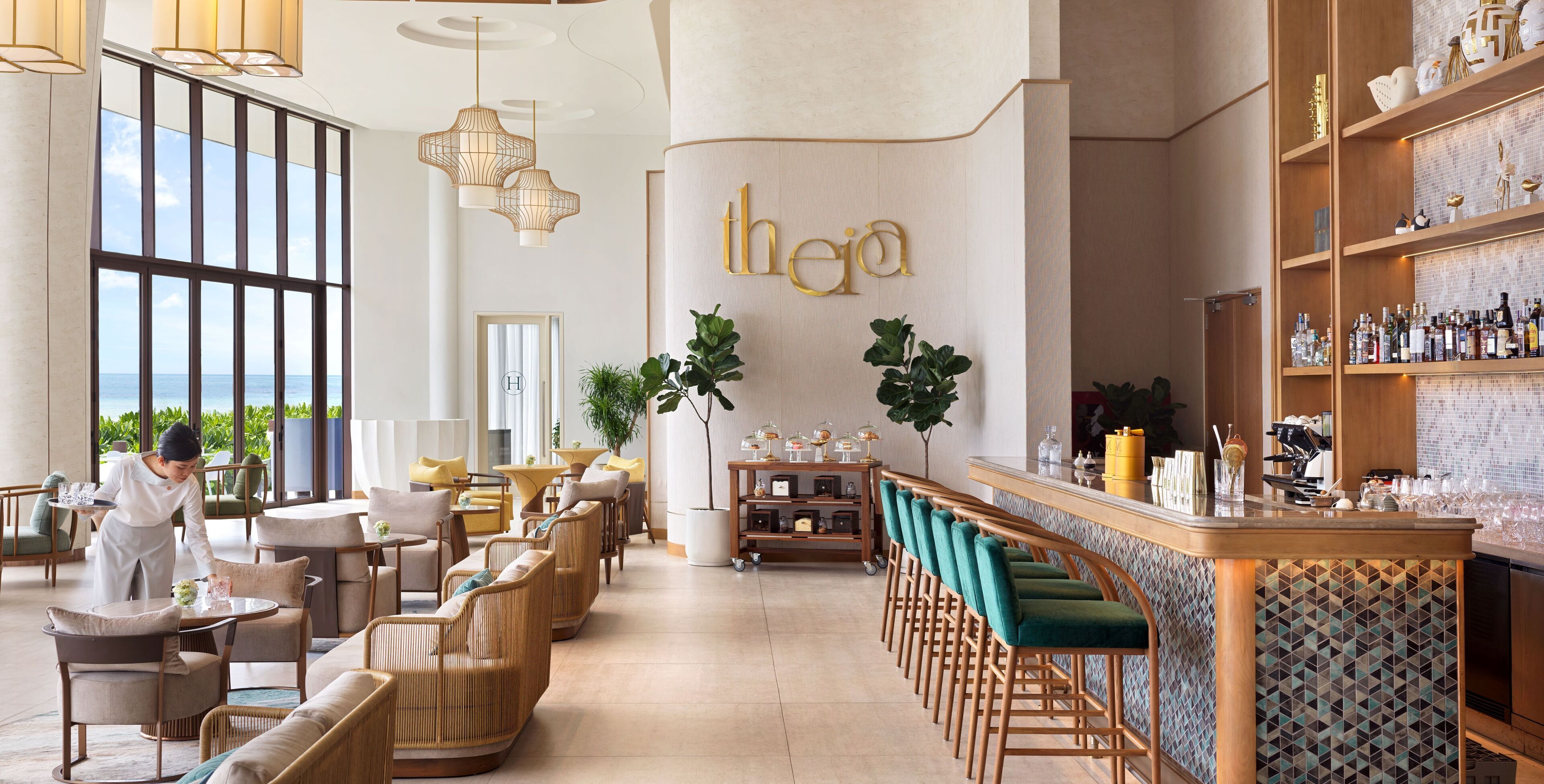 Un moderno vestíbulo de hotel con zona de bar, asientos y vistas al mar.