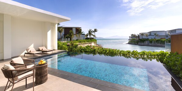 Ein Infinity-Pool mit freiem Blick auf den Ozean, umgeben von üppiger Vegetation und moderner Architektur.