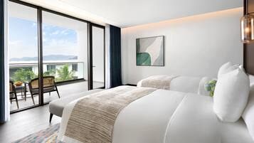 A modern hotel room with a balcony, a bed with white linens, a large abstract painting, and a hanging light fixture.