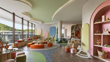 A children's playroom with colorful furniture, a large window, and a view of the outdoors.