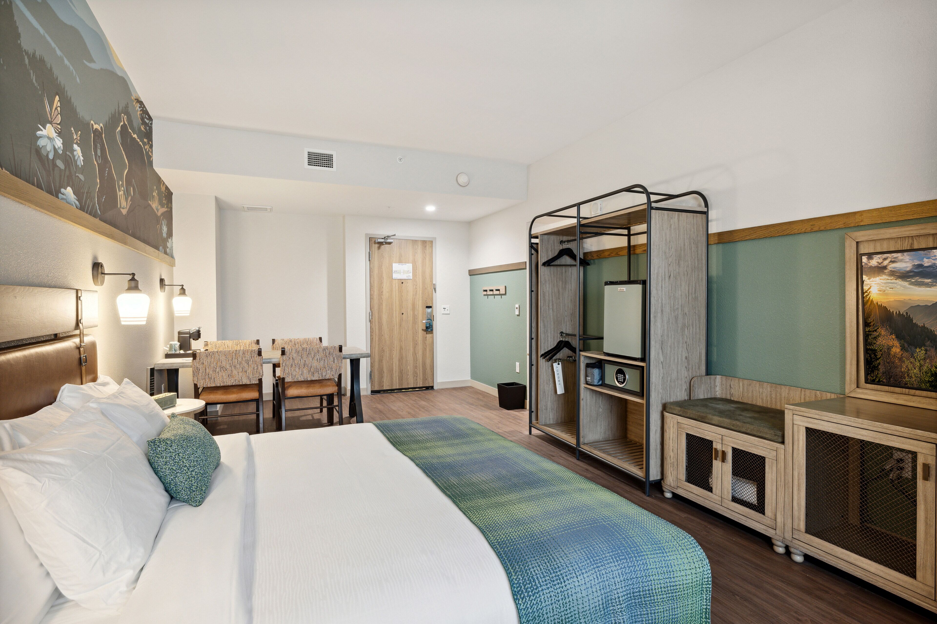 Una habitación de hotel con cama, escritorio, silla, armario y zona de ducha.