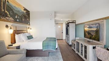 A hotel room with a bed, a TV, a desk, and a painting on the wall.