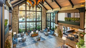 A spacious lobby with large windows, wooden beams, and a variety of seating arrangements. - HeartSong Lodge & Resort (Pigeon Forge)