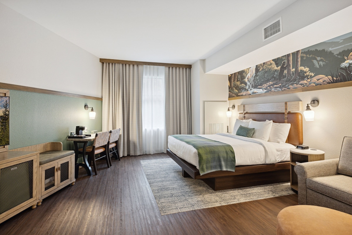 Een hotelkamer met een bed, een bureau, een stoel, een bank en een schilderij aan de muur.