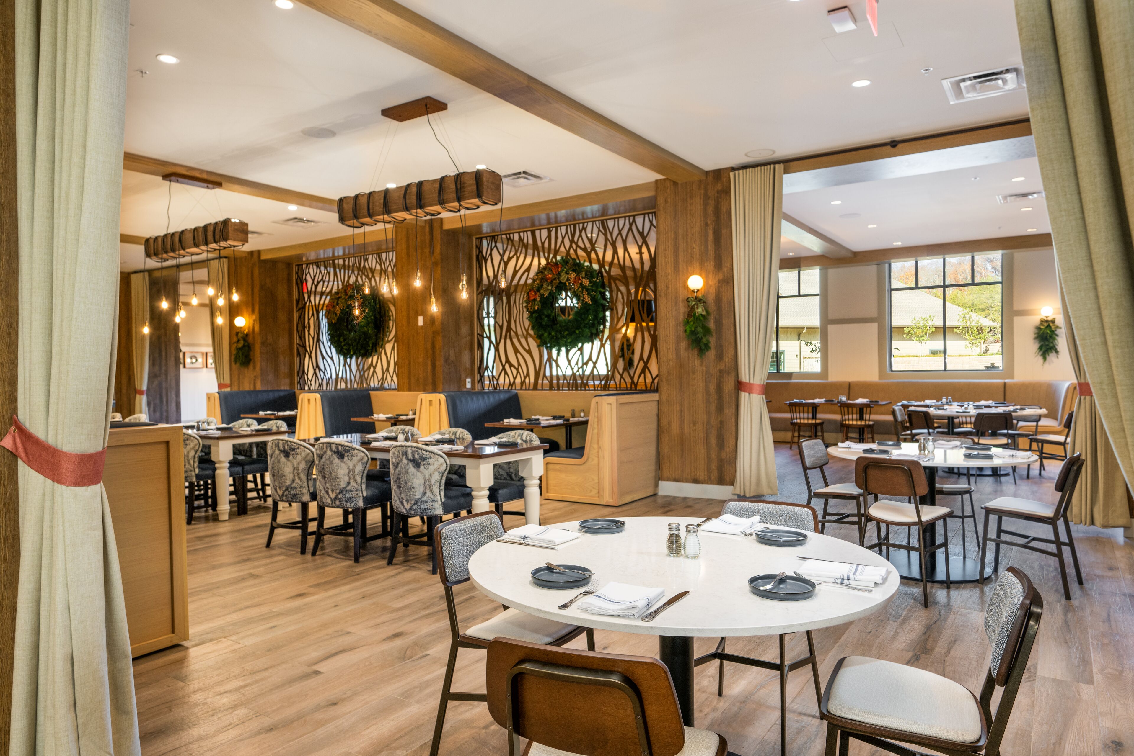 A restaurant with round tables, chairs, and a wooden interior.
