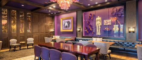 A conference room with a wooden table, purple chairs, and a blue sofa.