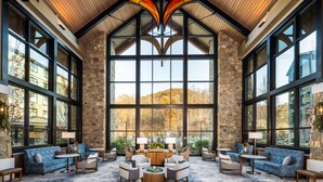 A spacious lobby with a high ceiling, large windows, and a central seating area with sofas and chairs. - HeartSong Lodge & Resort (Pigeon Forge)