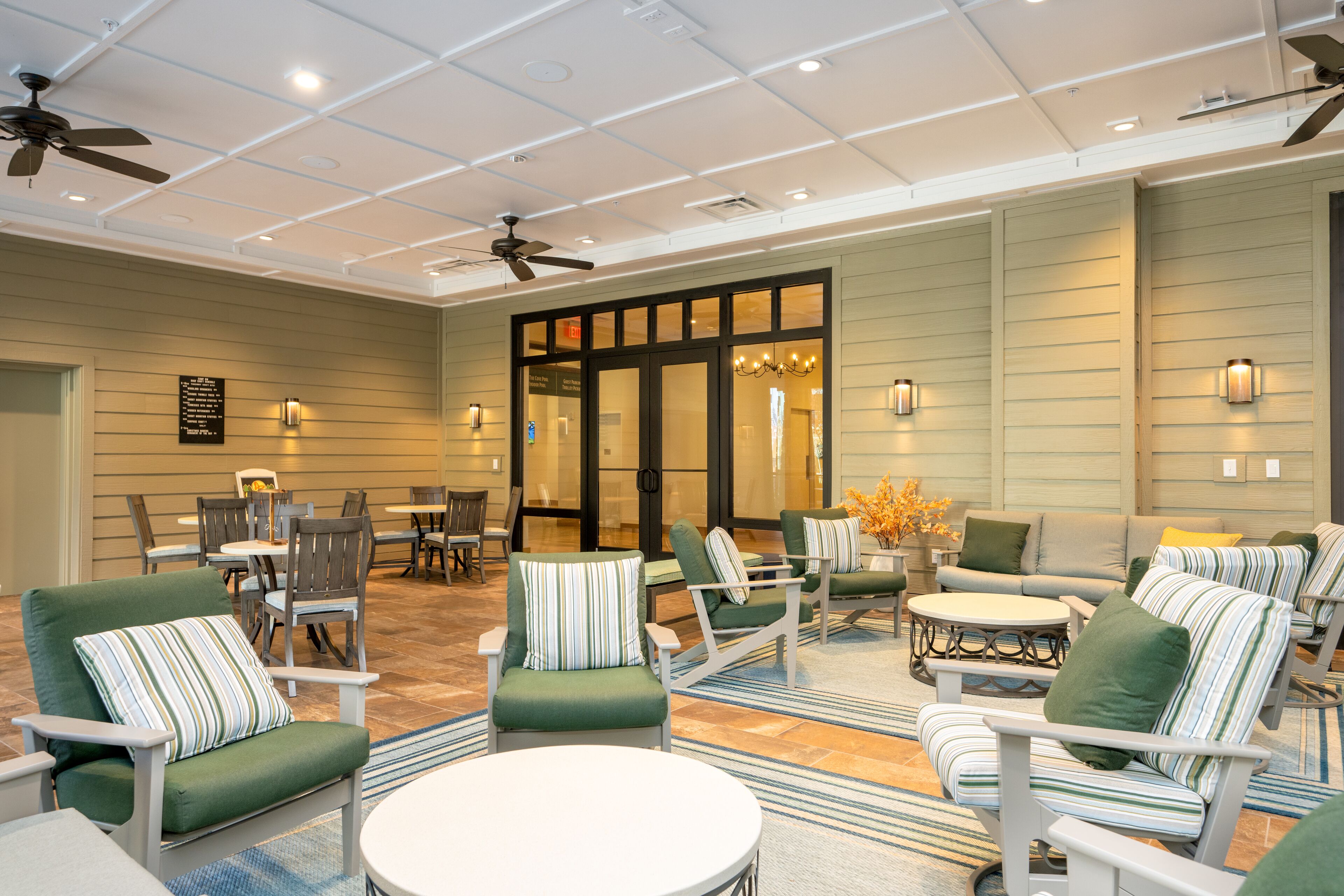 A spacious indoor area with multiple seating options including chairs and sofas, a round table, and a ceiling fan.