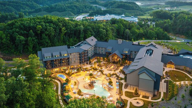 A resort with a large pool area, multiple buildings, and surrounding forested landscape. - HeartSong Lodge & Resort (Pigeon Forge)