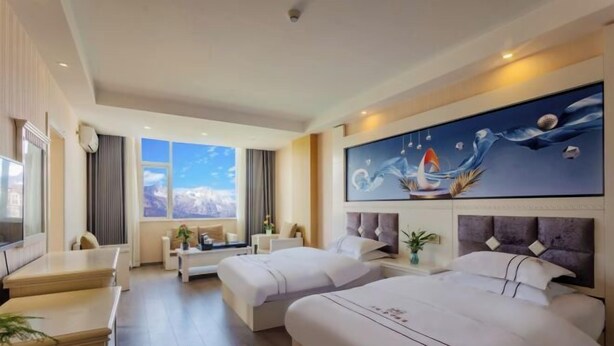 A hotel room with two beds, a desk, a sofa, a painting, and a view of the mountains. - Duomi Chain Hotel (Lijiang Ancient City) (Lijiang)