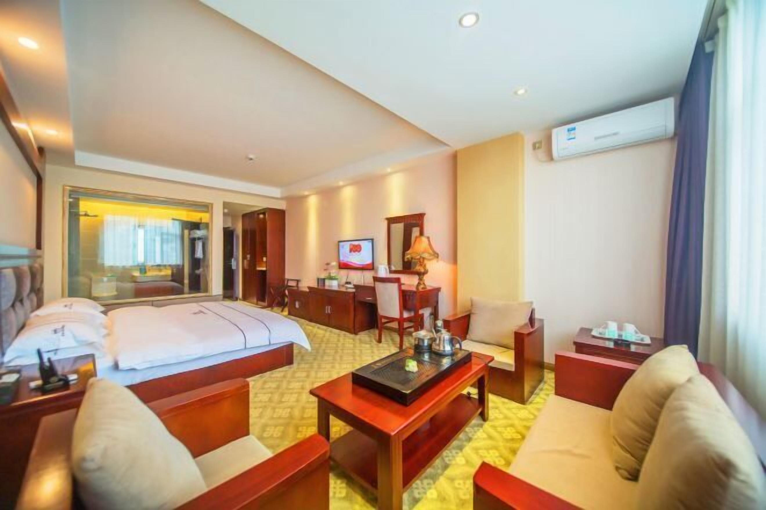 A hotel room with a bed, a desk, a TV, and a sofa.