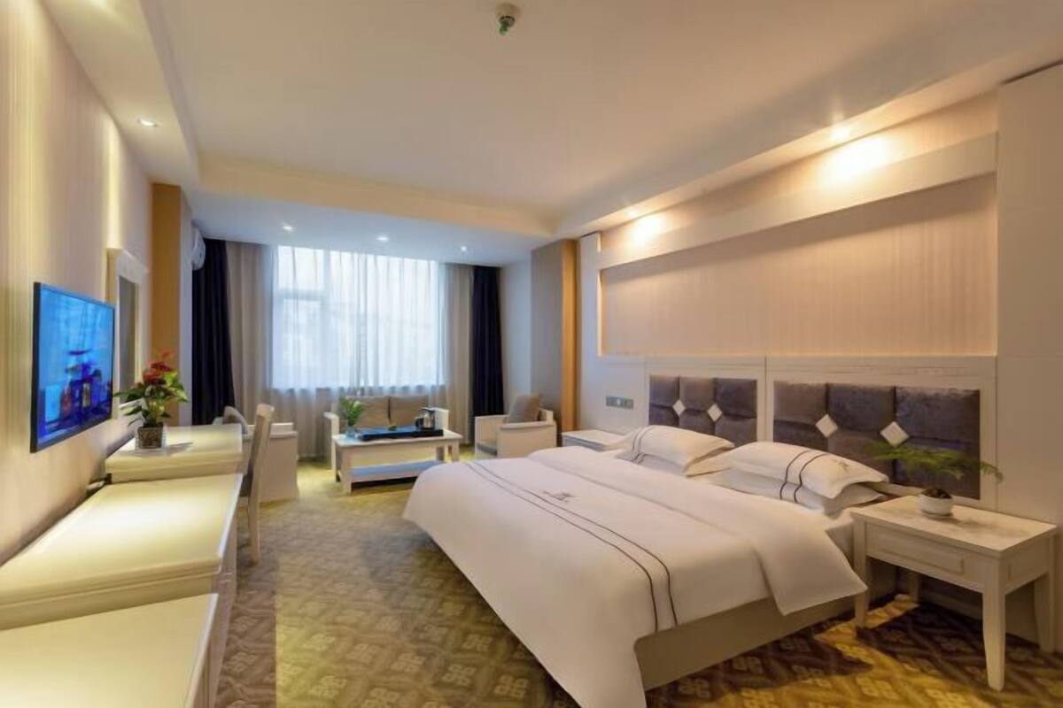 A hotel room with a large bed, bedside tables, a desk, and a chair.
