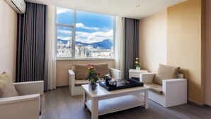 A modern living room with a large window, a sofa, a coffee table, and a side table. - Duomi Chain Hotel (Lijiang Ancient City) (Lijiang)