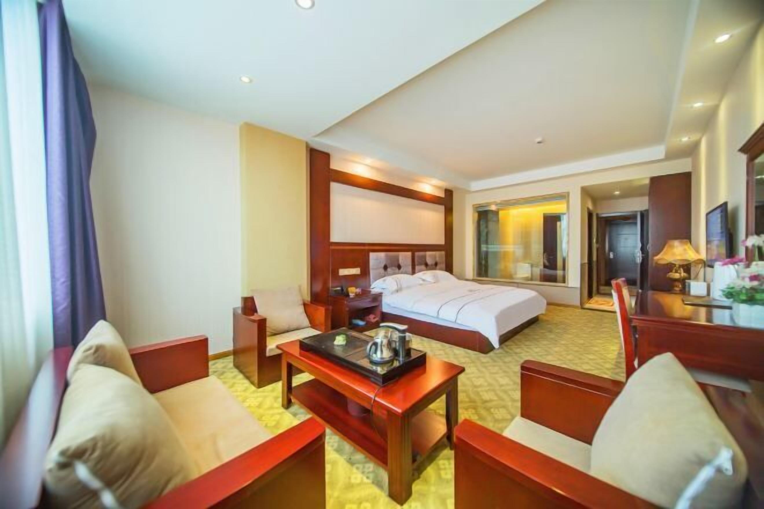 Une chambre d’hôtel avec un lit, un bureau et deux chaises.