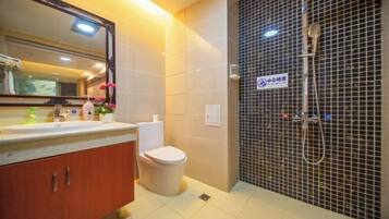 A bathroom with a sink, mirror, toilet, and shower area.