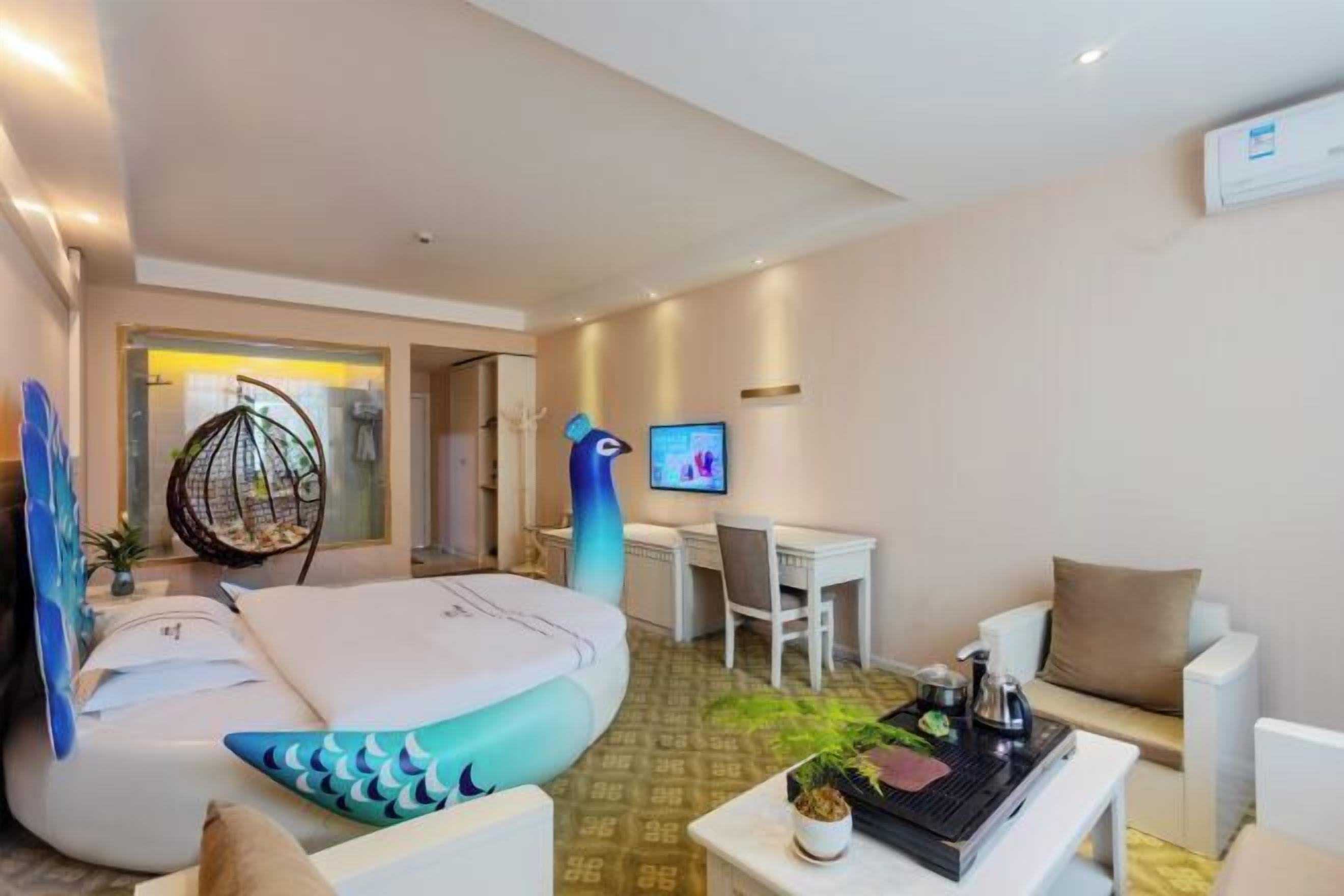 Una habitación de hotel moderna con una zona de estar circular, un escritorio, un televisor y una mesa de comedor con una planta.