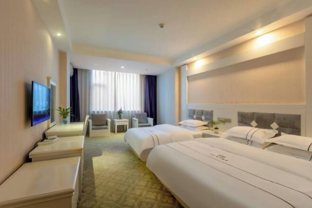 A hotel room with two beds, a TV, a desk, and a chair.