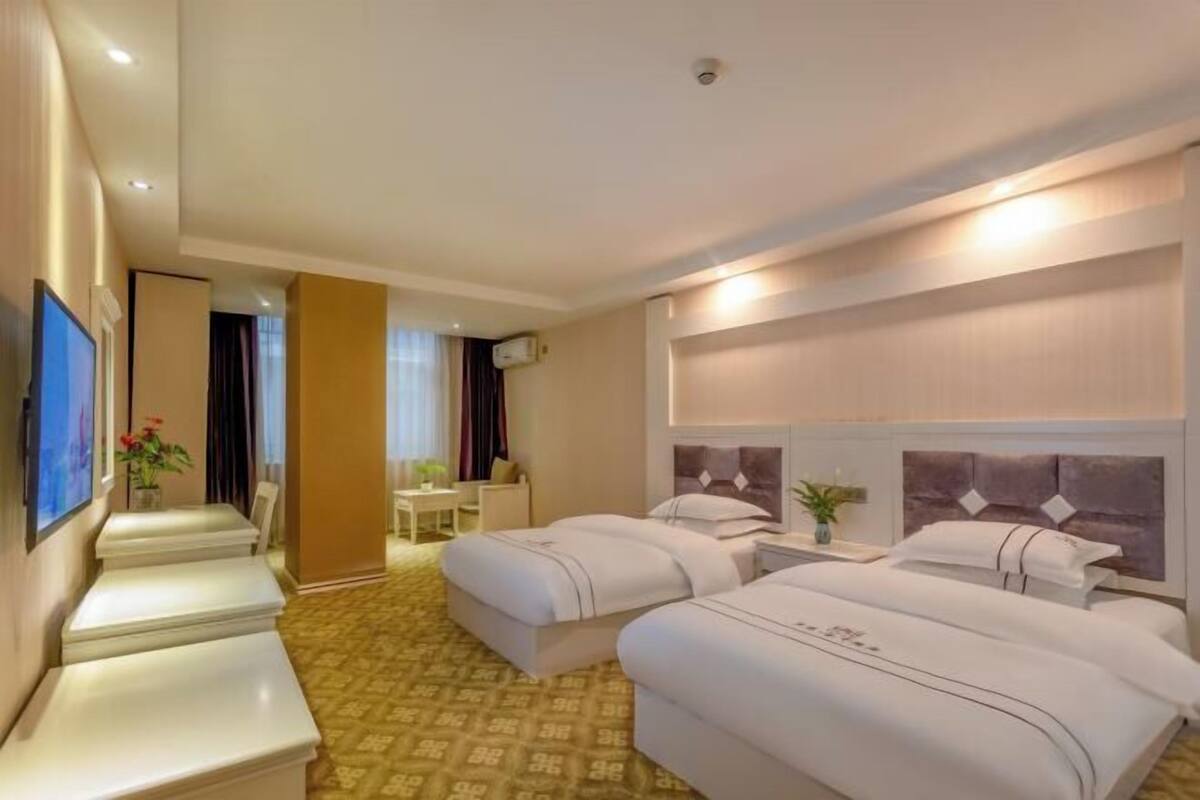 A hotel room with two beds, a TV, a desk, and a chair.