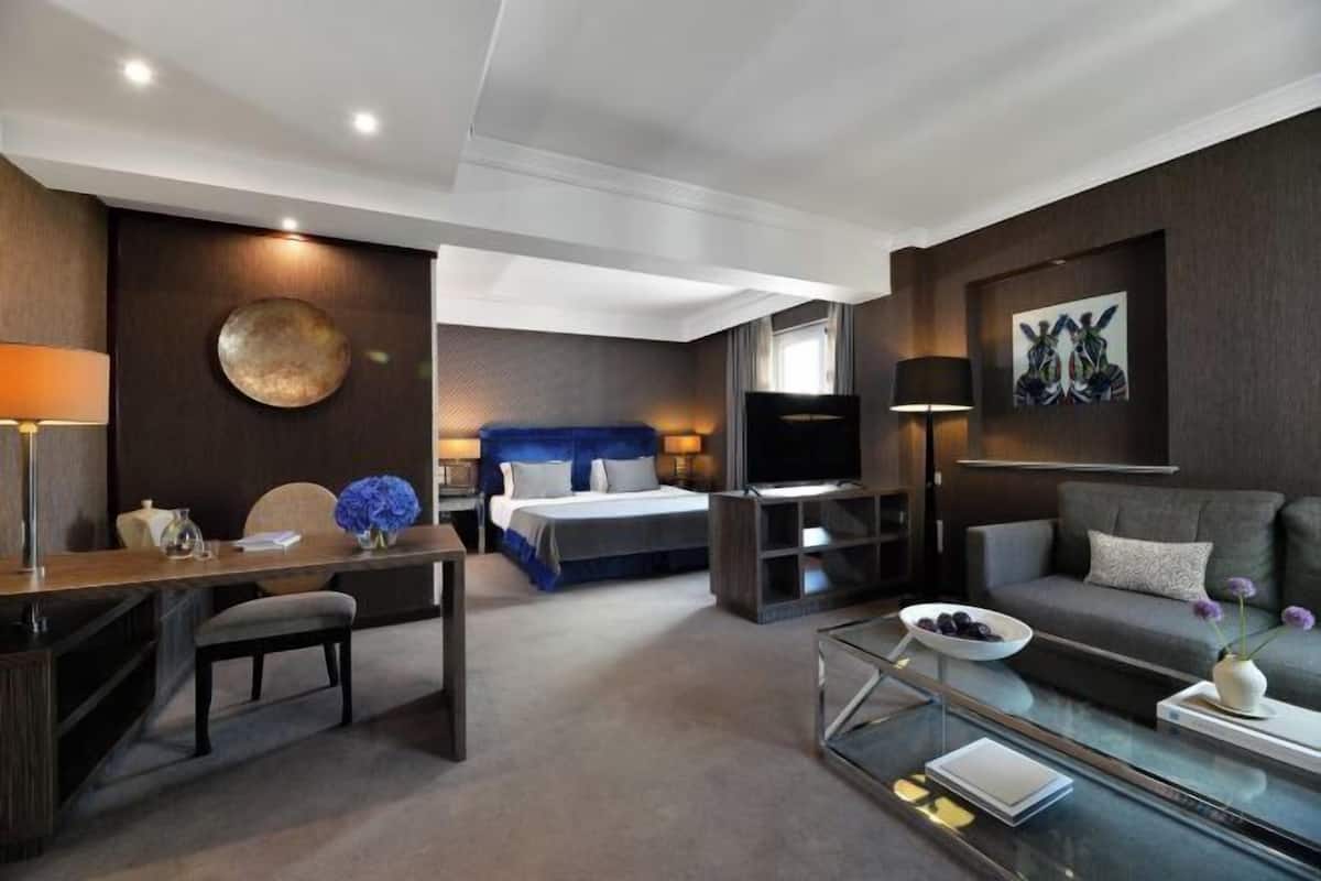 Une chambre d’hôtel moderne équipée d’un lit, d’un bureau, d’un canapé, d’une télévision et d’une table basse en verre.