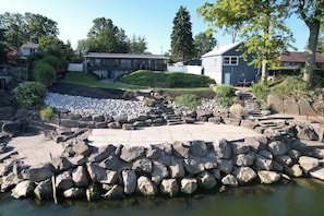 Stroll through a serene garden with a small pond and stone pathway, surrounded by lush greenery and peaceful homes.