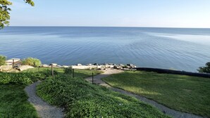 Ein Küstenweg führt zu einer felsigen Uferlinie, mit freiem Blick auf das Meer.