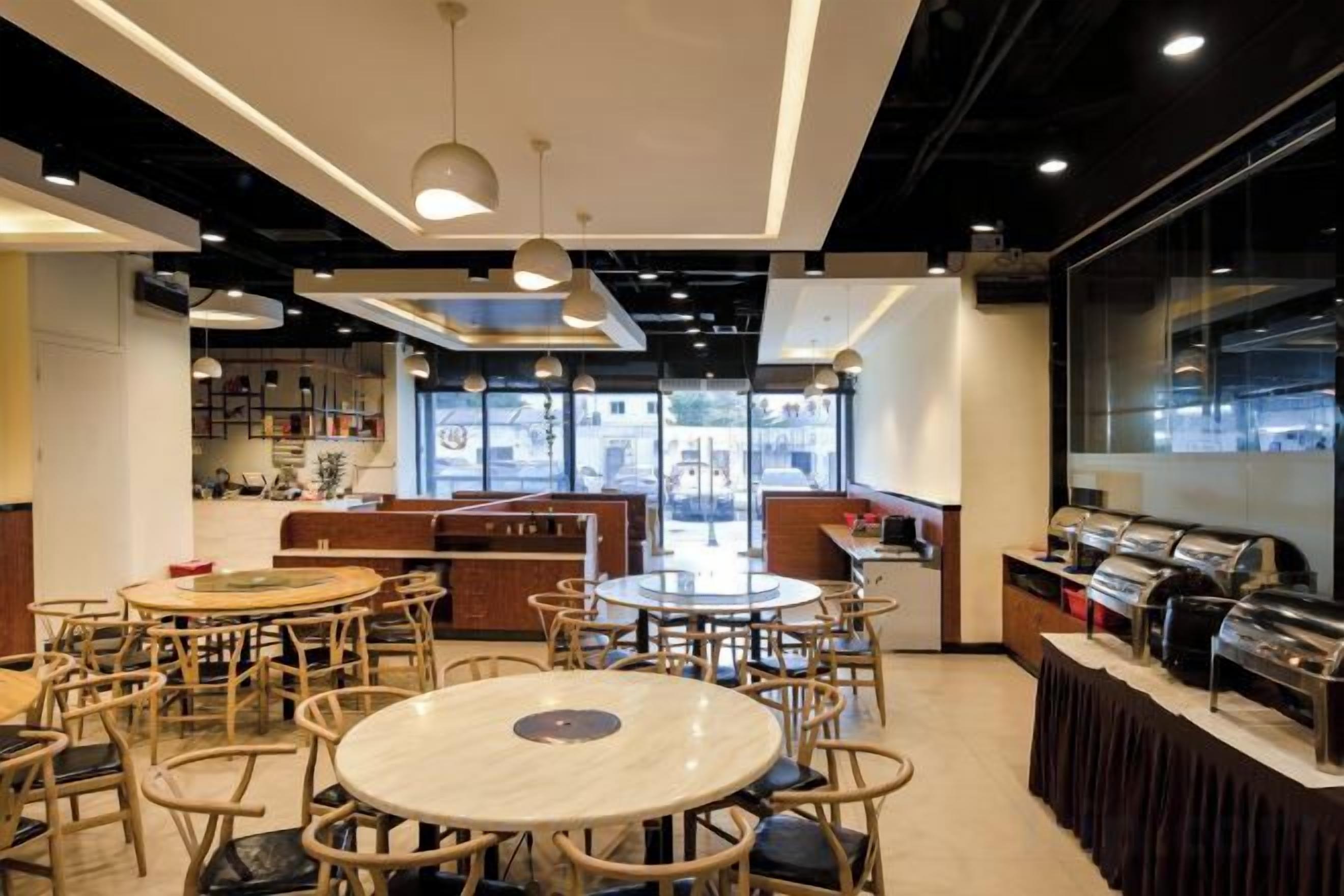 A restaurant with round tables and chairs, a bar area, and large windows.