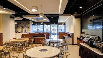 A restaurant with round tables and chairs, a bar area, and large windows.