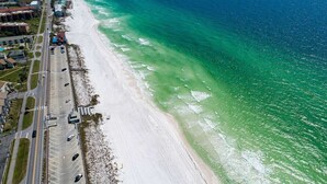An aerial view of a coastal road with a beach on one side and buildings on the other. - Luxurious Condo with Zero Entry Pool & Gated Beach (Miramar Beach)