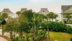 A beachfront property with multiple houses, a well-maintained garden, and a view of the ocean. - Luxurious Condo with Zero Entry Pool & Gated Beach (Miramar Beach)