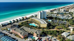 An aerial view of a coastal hotel with a pool, beachfront, and multiple buildings. - Luxurious Condo with Zero Entry Pool & Gated Beach (Miramar Beach)