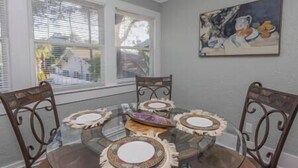 A dining area with a glass table surrounded by four chairs, each with a decorative plate. - ArtSea2. 2BR · Upstairs w/Ample Parking | Near Beaches & LECOM (Bradenton)