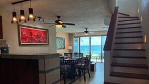 A spacious kitchen with a dining area, large windows, and a staircase leading to a balcony. - Cancun Ocean Front Family Villa 18  at Villas Nizuc (Cancun)