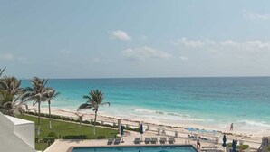 A pool area with lounge chairs and umbrellas, overlooking a beach with palm trees and the ocean. - Cancun Ocean Front Family Villa 18  at Villas Nizuc (Cancun)