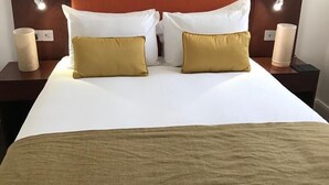 Une chambre d’hôtel avec un grand lit, deux tables de chevet et un tableau encadré au mur.