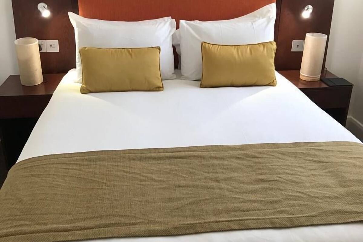 Une chambre d’hôtel avec un grand lit, deux tables de chevet et un tableau encadré au mur.