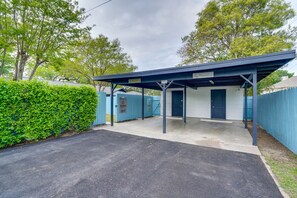 Ein überdachter Außenbereich mit einem weißen Gebäude, einem blauen Zaun und einer Hecke.