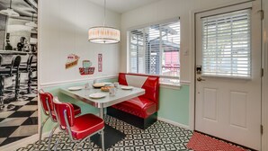 Un clásico restaurante con mesas de estilo retro, un banco rojo, una mesa blanca y sillas de cromo.