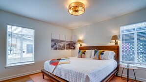 Un dormitorio con una cama grande, dos lámparas de noche, una mesita y vistas al exterior por la ventana.