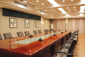 Un salón de conferencias con una mesa larga, sillas y una pantalla para proyector.