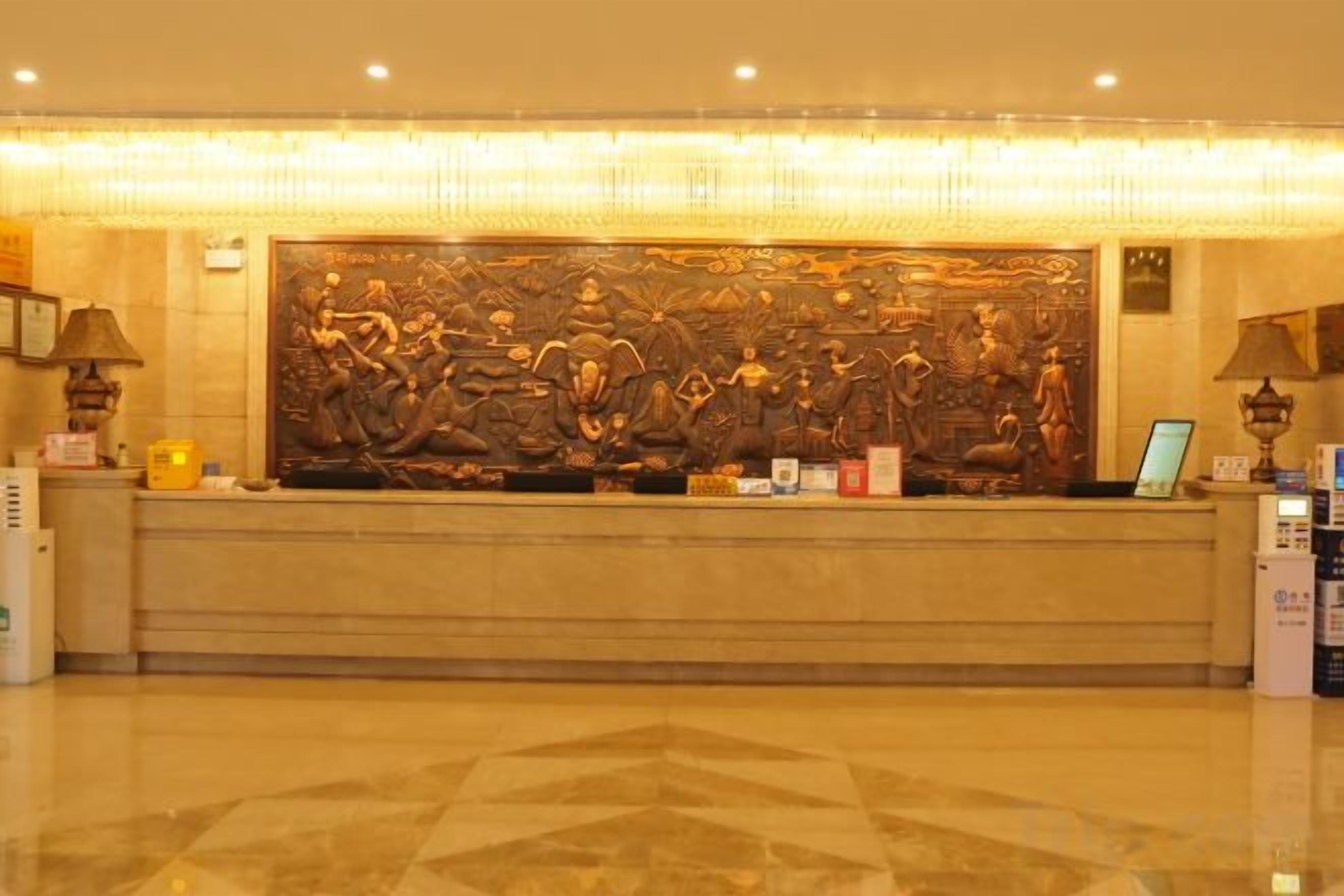 A reception desk with a large decorative panel above it, a polished marble floor, and a lamp on the right side.