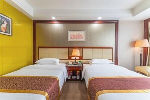 A hotel room with two beds, a nightstand, a lamp, and a painting on the wall. - Huakang International Hotel (Qianjiang)